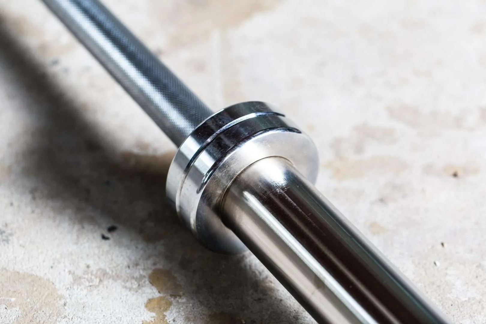 Close-up of a chrome barbell sleeve on concrete