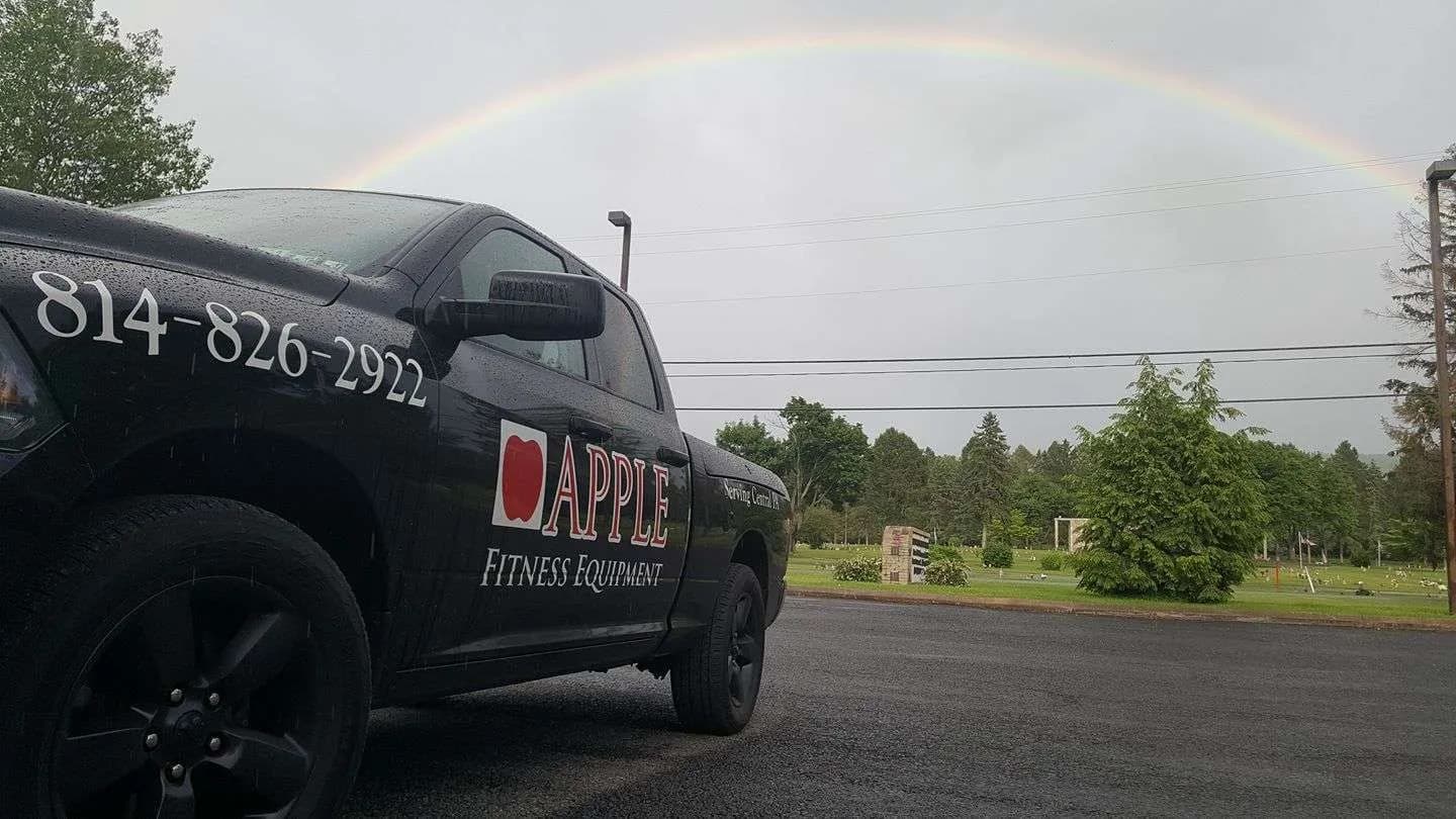 The Apple Fitness Equipment service truck, lettered Serving Central PA, under a rainbow