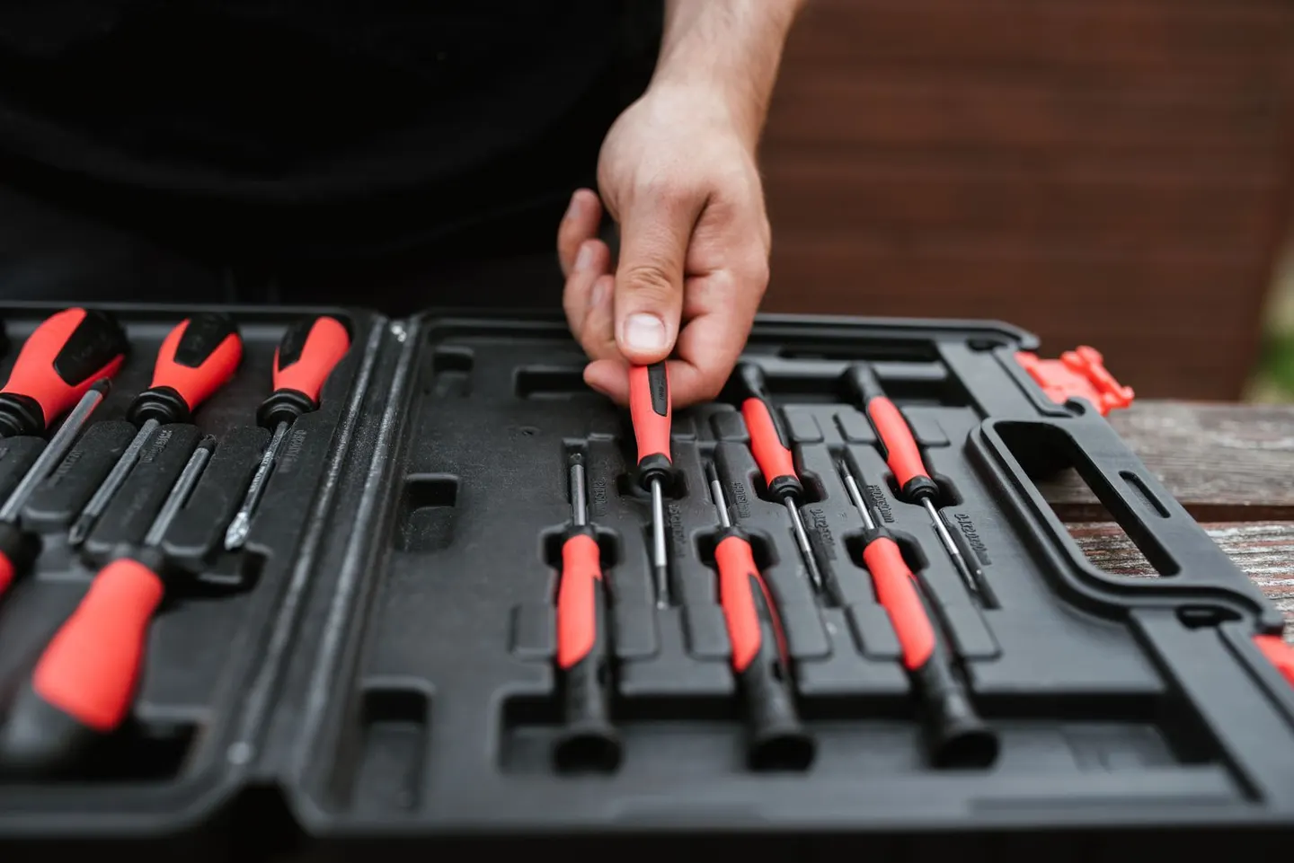A hand picking a screwdriver from an open toolbox
