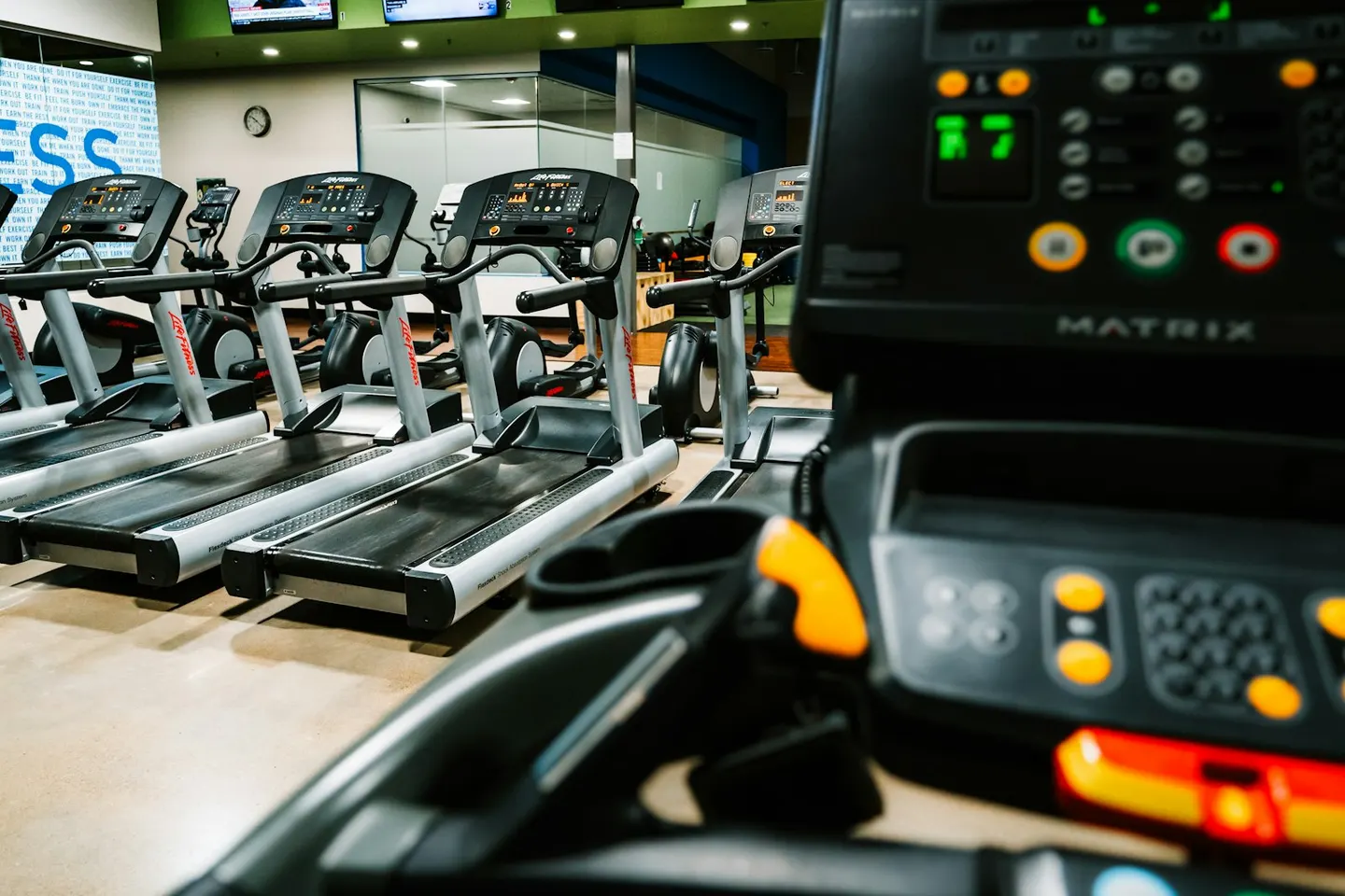 A Matrix treadmill console in front of a row of commercial treadmills