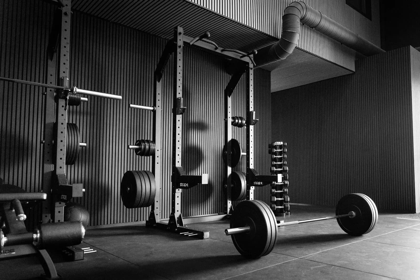 Empty gym with a power rack, barbells, and plates